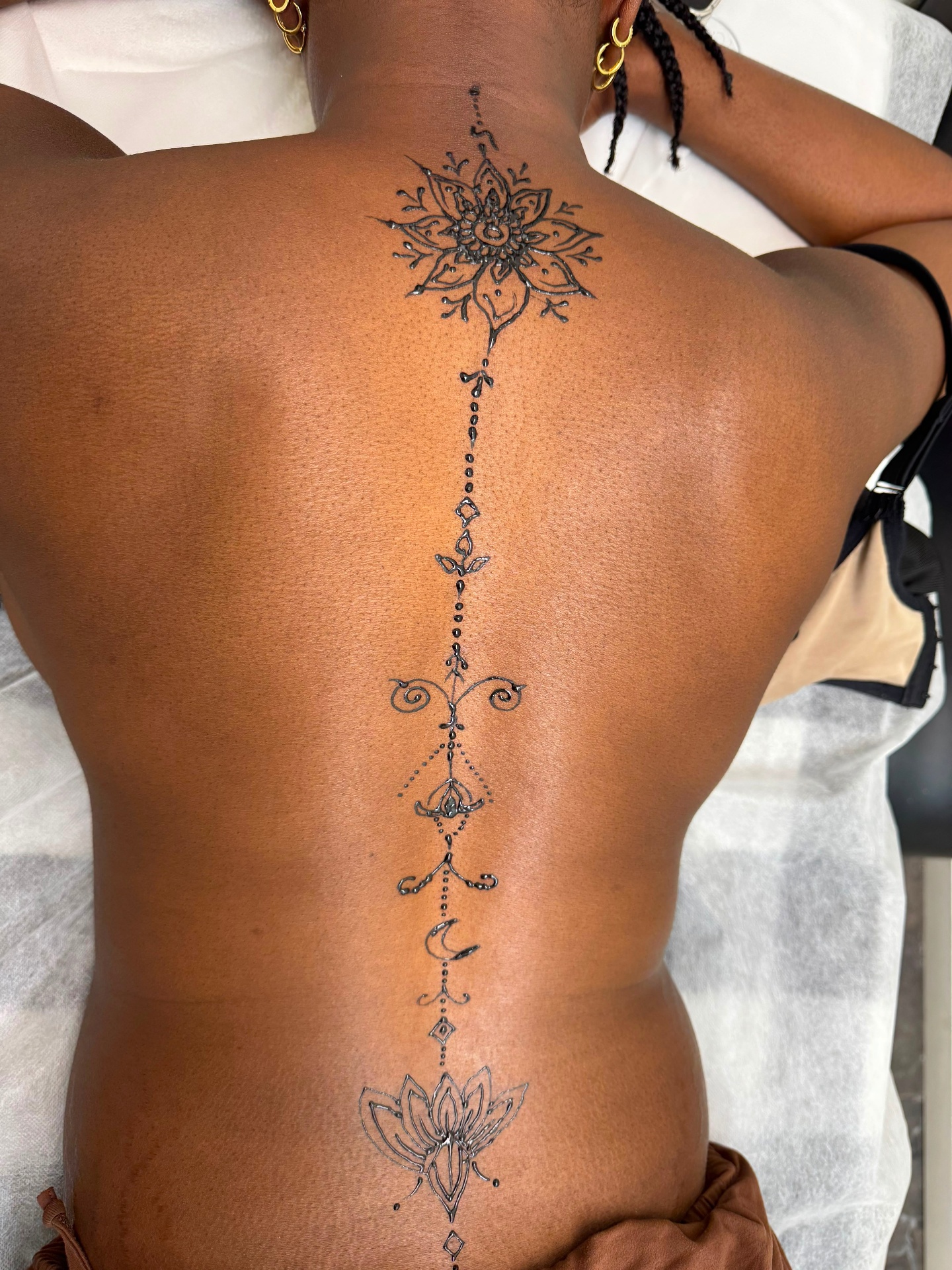Spine henna tattoo with mandala and lotus design on woman's back at Magical Waxing Atlanta