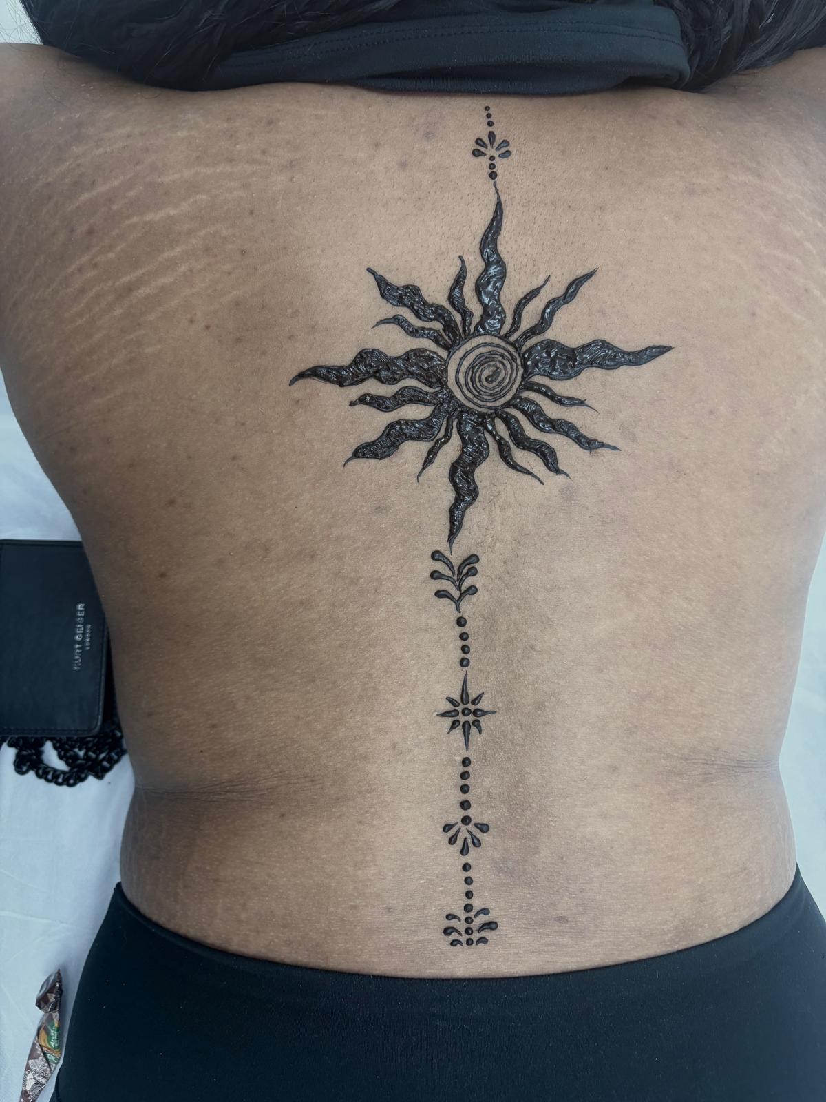 Fresh black henna sun and spine tattoo on back — bold body art at Magical Waxing Atlanta