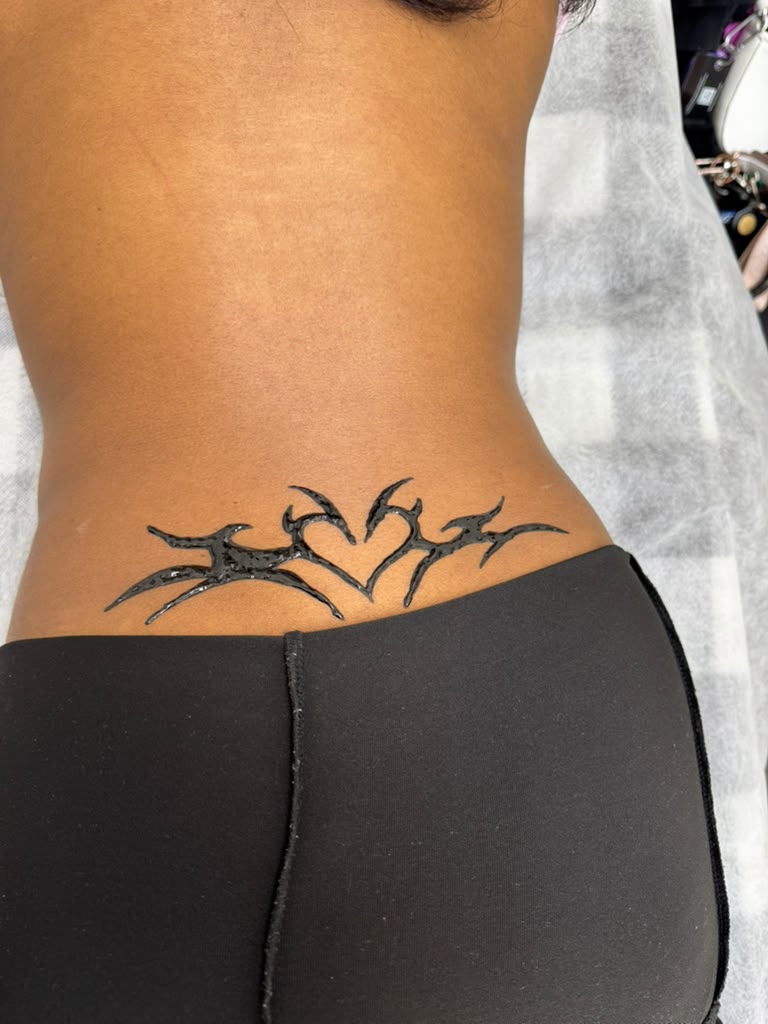 Fresh black henna tribal heart design on lower back — Magical Waxing Atlanta henna artist