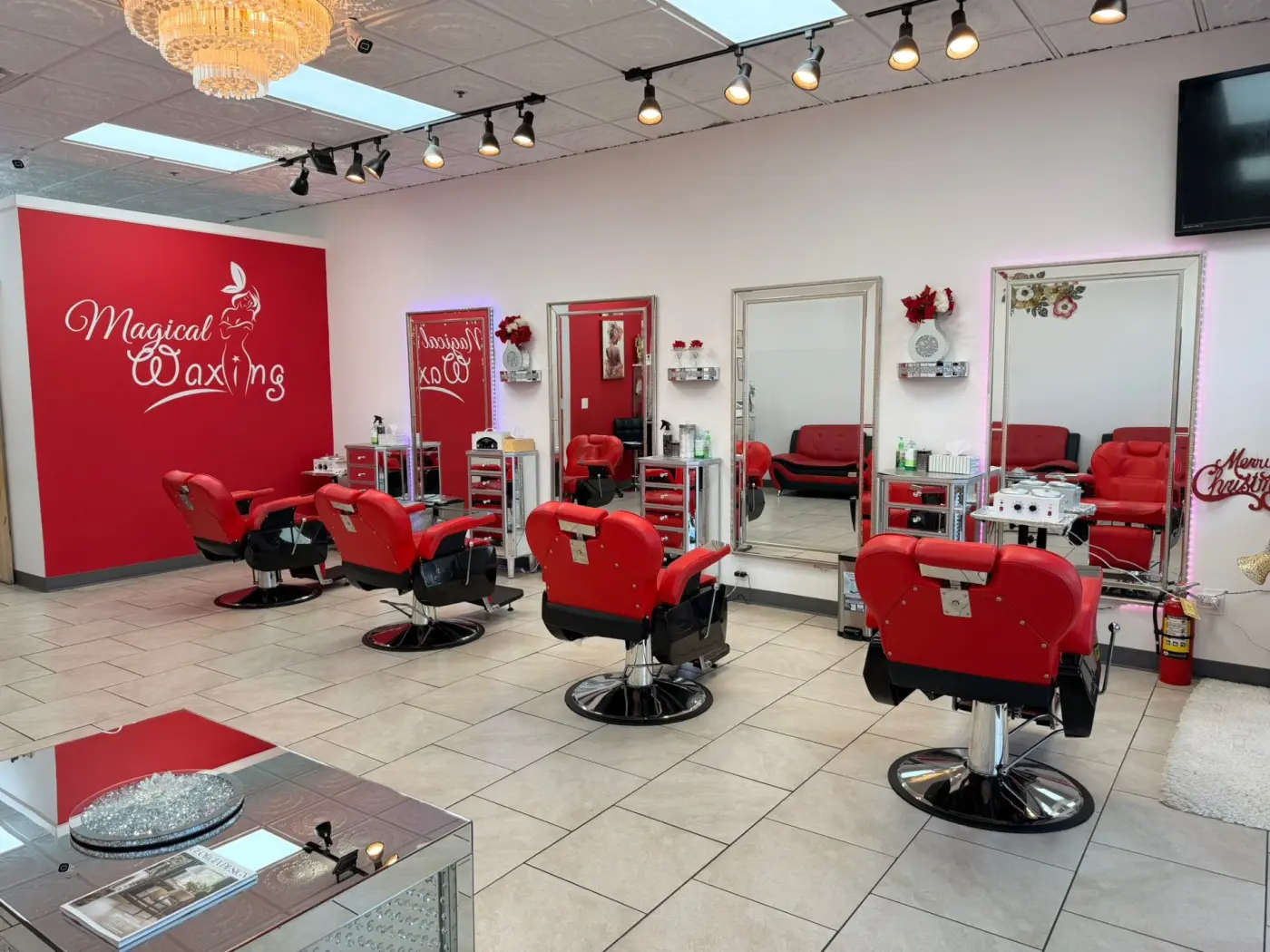 Interior del salón Magical Waxing con pared roja de marca, sillas profesionales y candelabro de cristal — salón de depilación en Atlanta