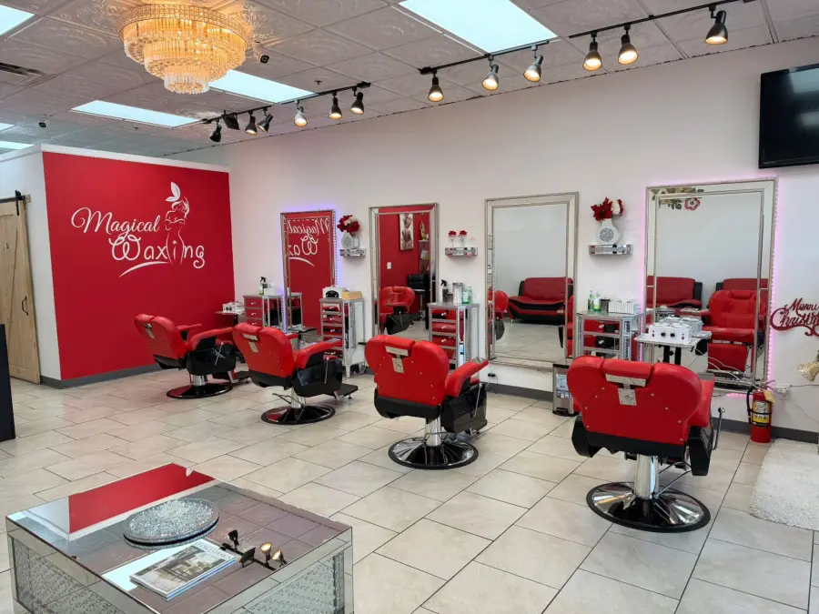 Wide view of Magical Waxing salon with branded red accent wall, multiple styling stations, and premium interior design