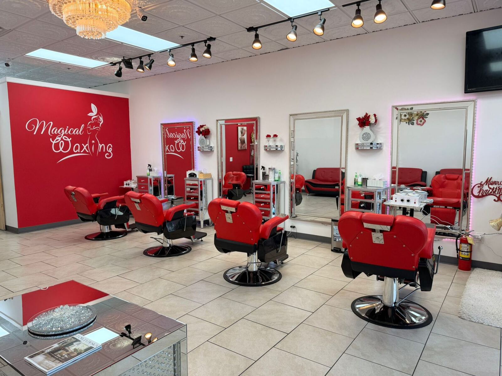 Magical Waxing salon interior with branded red wall, professional styling chairs, and crystal chandelier — Atlanta waxing salon